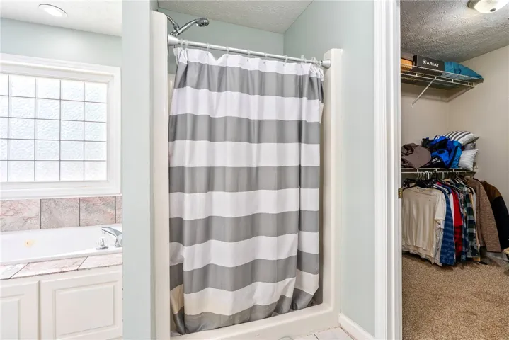 This bathroom features a shower, a relaxing soaking tub, and an adjacent walk-in closet.