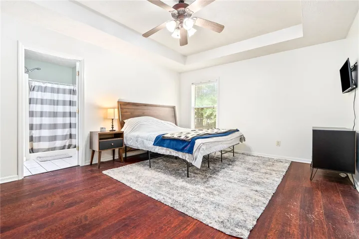 This primary bedroom suite offers a cozy retreat with rich hardwood flooring and an adjoining private bath.