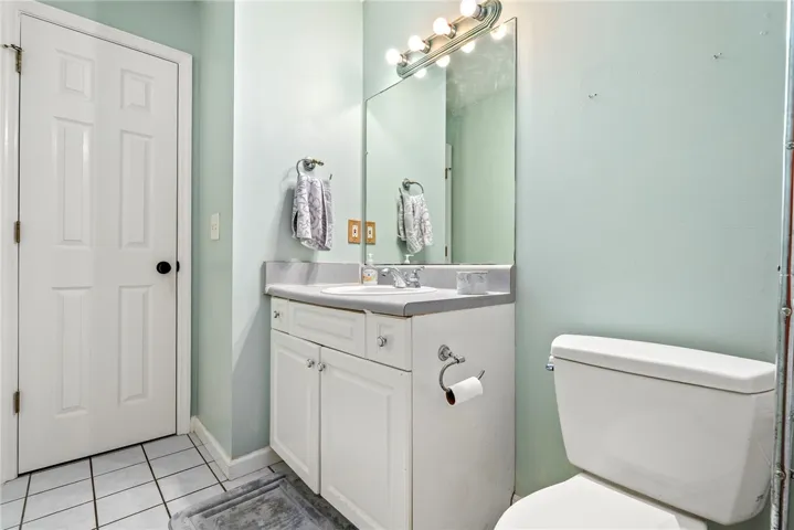 A well-appointed bathroom with tile flooring features a single vanity, mirror, and toilet.