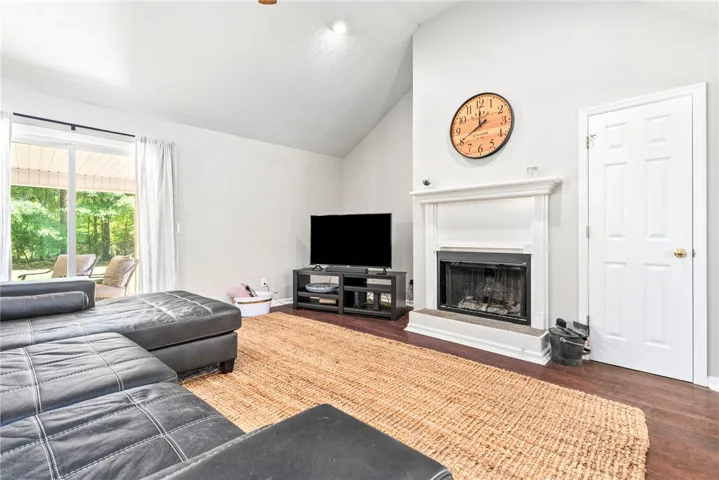 This living room features rich wood flooring, a striking fireplace, and sliding glass doors that open to a serene outdoor space.