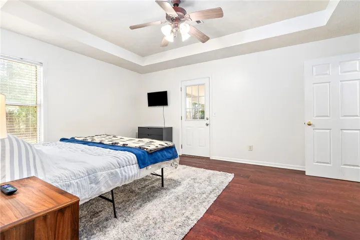 This bedroom offers elegant tray ceilings and rich wood flooring, complementing the outdoor access.