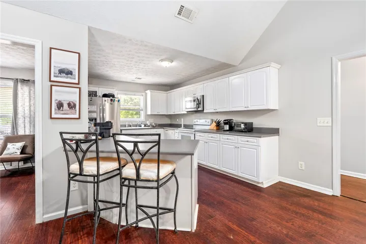 This kitchen showcases ample white cabinetry, sleek countertops, and rich hardwood flooring, ready for culinary endeavors.