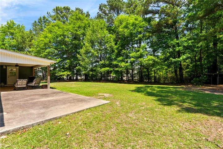This verdant backyard features a comfortable patio area, perfect for relaxed outdoor enjoyment and surrounded by mature trees.
