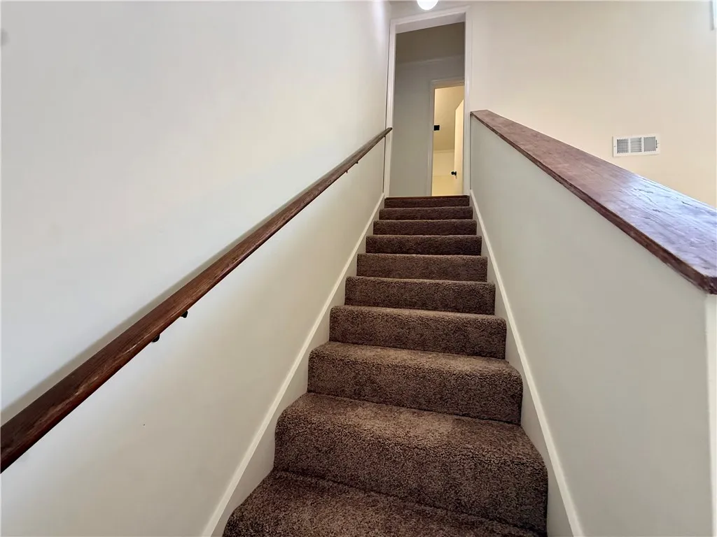 Ascend to comfort on this carpeted staircase, featuring rich wood handrails for a touch of elegance.