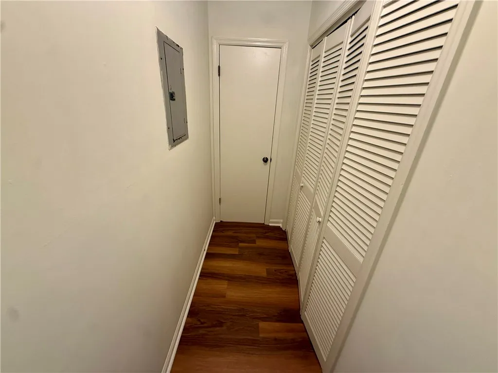 Hardwood flooring extends through this practical hallway, featuring louvered bi-fold doors.