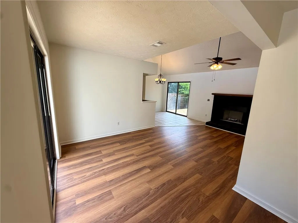 A well-lit living area features vaulted ceilings, rich hardwood flooring, and a cozy fireplace.
