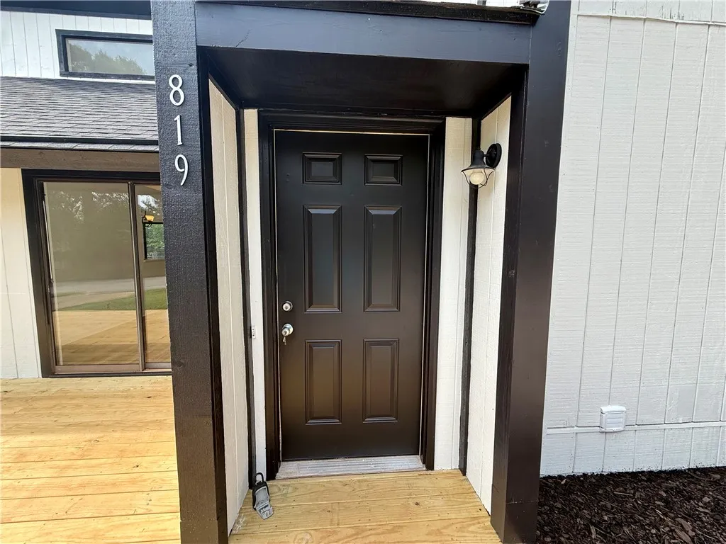 A welcoming front entrance featuring a dark paneled door and modern outdoor lighting.