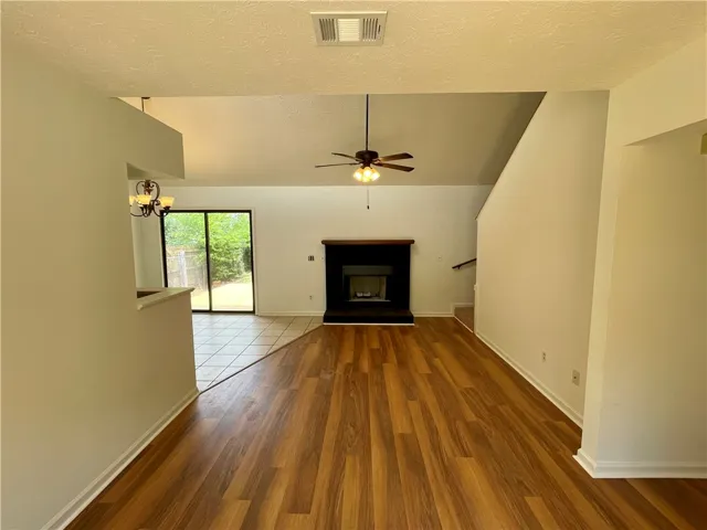 A spacious common area boasts warm wood-look flooring and a cozy fireplace, perfect for gathering.