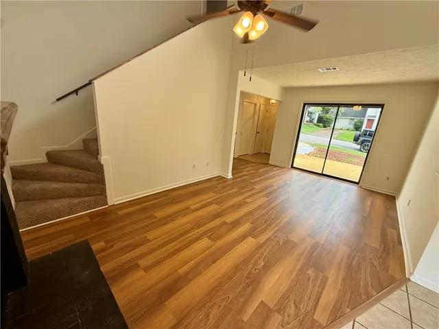A well-lit living space features rich hardwood flooring and a vaulted ceiling.