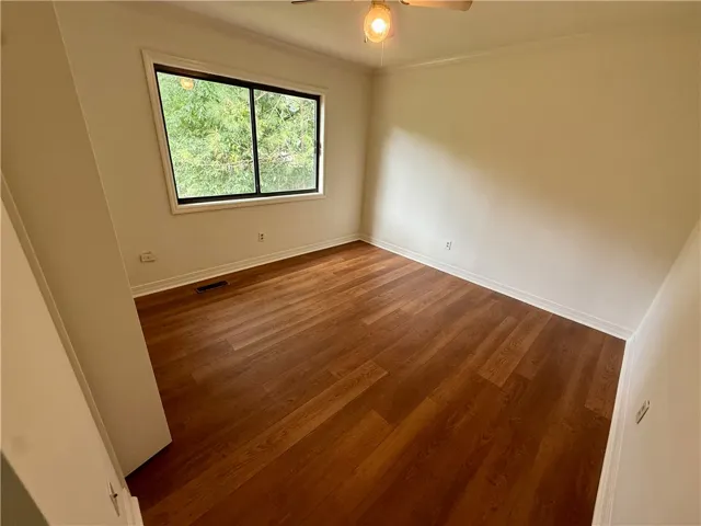 Rich hardwood flooring complements ample natural light in this serene and ready-to-personalize bedroom space.