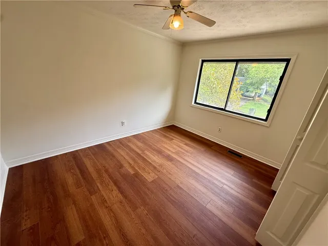 Natural light illuminates rich hardwood flooring in this cozy bedroom.