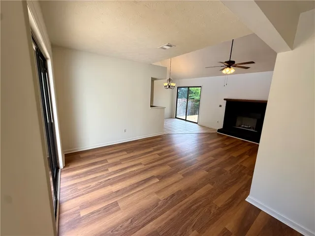 A well-lit living area features vaulted ceilings, rich hardwood flooring, and a cozy fireplace.