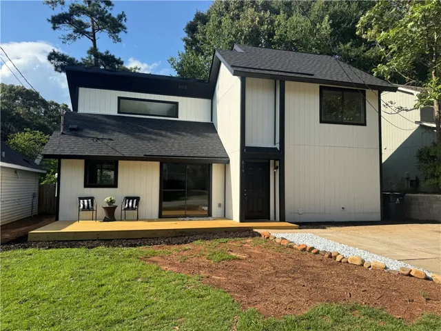A newly constructed modern dwelling features an inviting deck and mature landscaping.