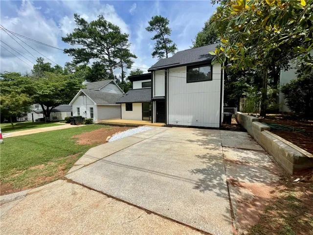 A modern facade with crisp lines and a welcoming deck overlooks a verdant lawn.