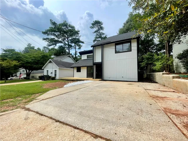 Modern architecture defines this dwelling, complemented by a large concrete driveway and mature surrounding trees.
