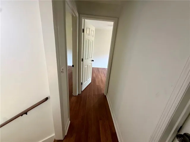 A well-lit hallway with gleaming wood floors connects multiple rooms.