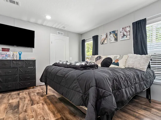 This restful bedroom features warm wood flooring and ample natural illumination.