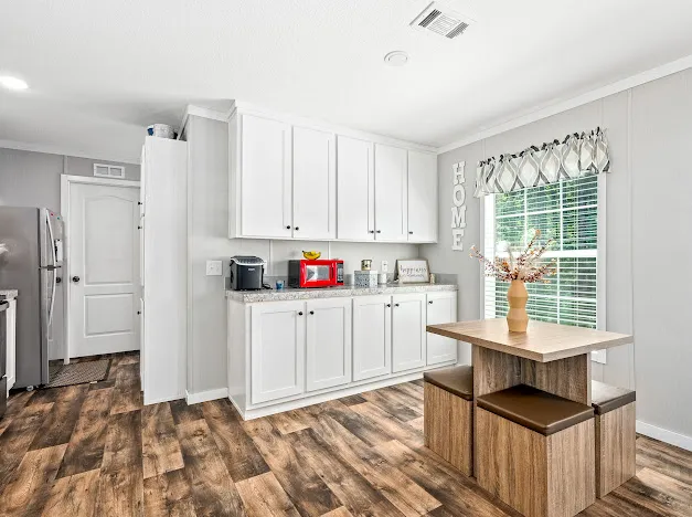 This galley kitchen presents a functional layout, featuring white cabinetry and robust wood-look flooring.