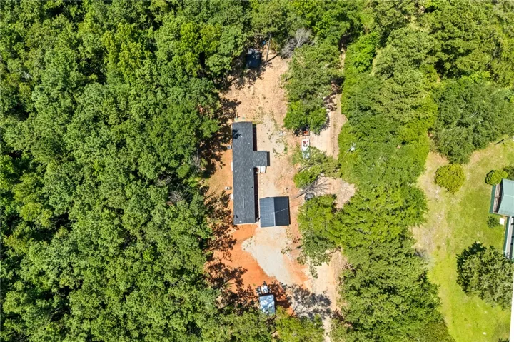 An aerial perspective reveals a secluded home nestled amongst dense, verdant woodlands.