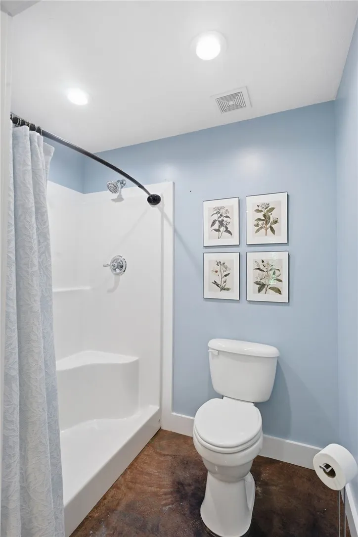 Functional full bathroom featuring a stand-up shower and toilet, well-lit by overhead recessed lights.