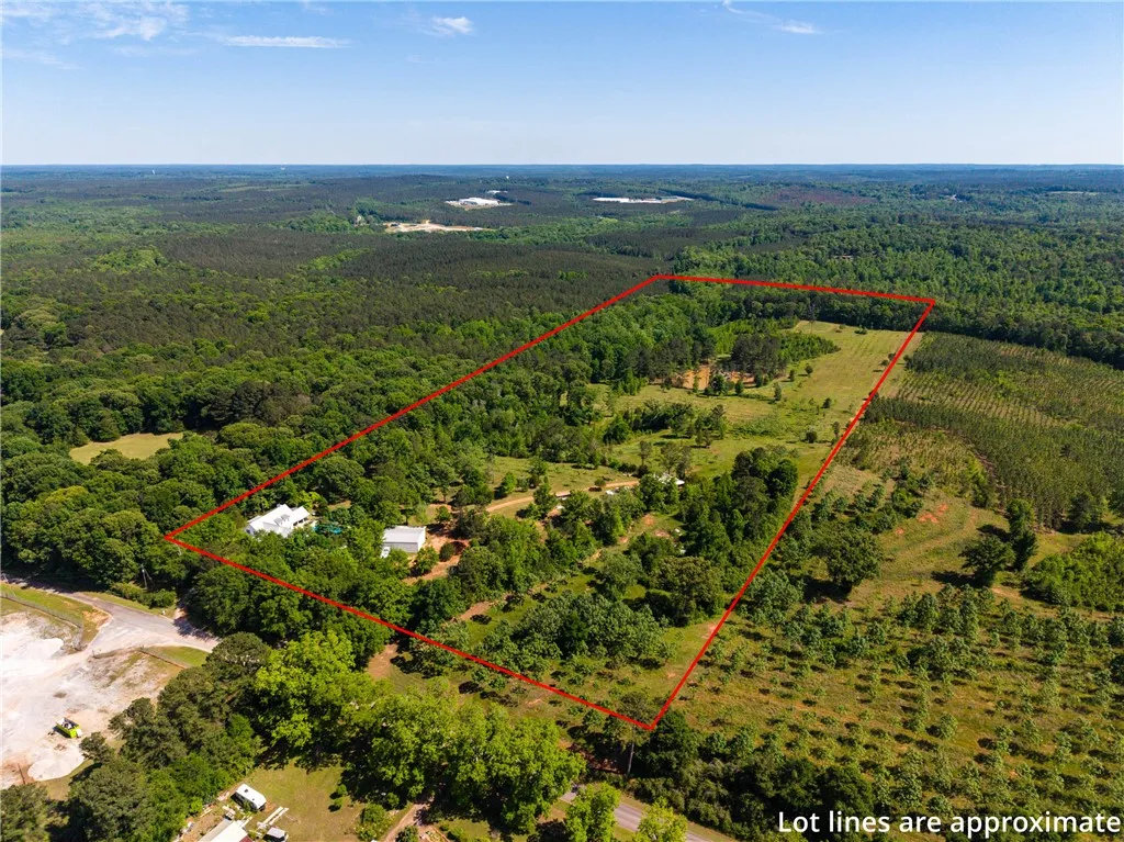 An aerial perspective reveals a vast, verdant lot with a mix of woodlands and open fields, bordered by more dense forestry.