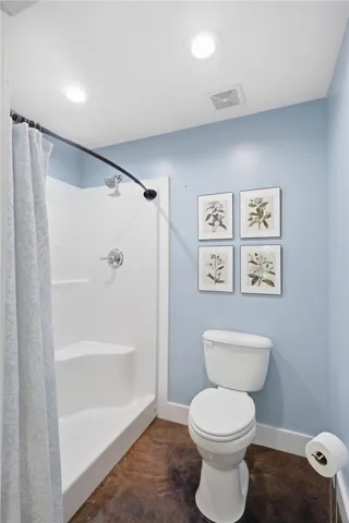 Functional full bathroom featuring a stand-up shower and toilet, well-lit by overhead recessed lights.