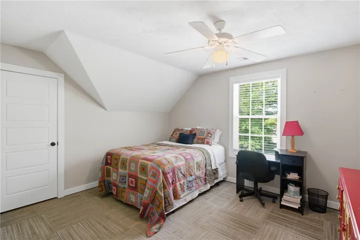 This cozy bedroom features a sloped ceiling and a large window, offering a pleasant and airy atmosphere.