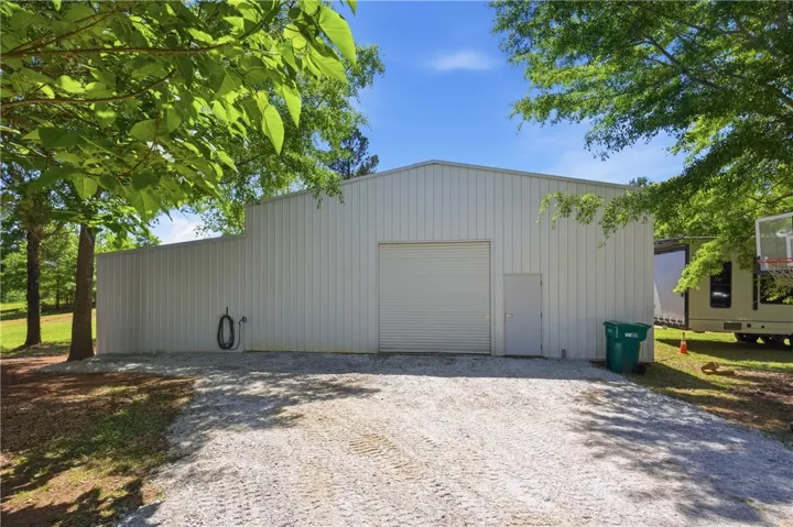 This metal outbuilding offers exceptional storage and utility, framed by verdant trees under a clear sky.