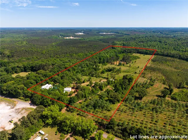 An aerial perspective reveals a vast, verdant lot with a mix of woodlands and open fields, bordered by more dense forestry.