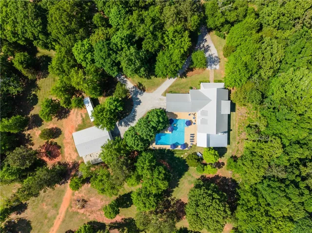 An aerial perspective reveals a secluded estate featuring a private pool and extensive wooded surroundings.