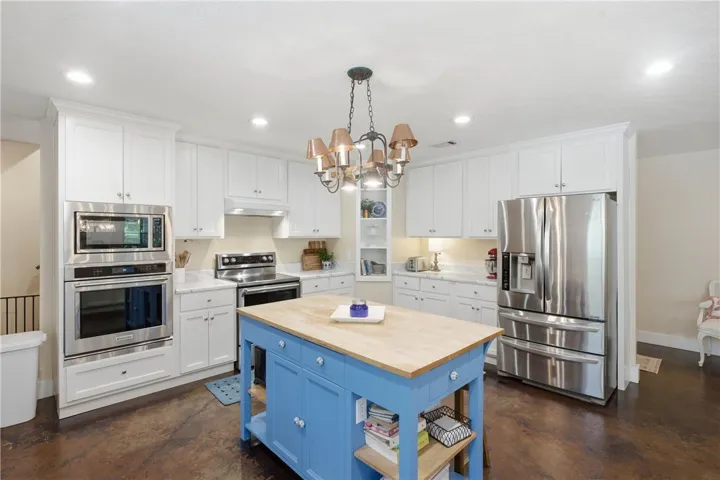 This kitchen showcases a central island, ample cabinetry, and essential cooking appliances for effortless meal preparation.