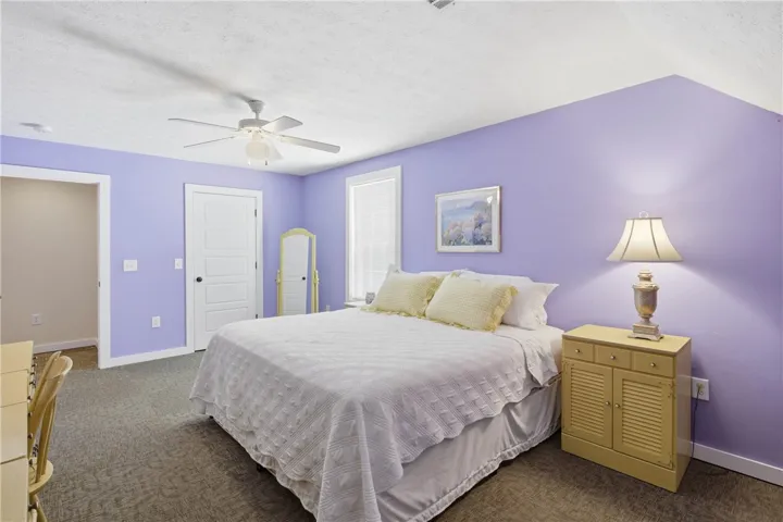 This tranquil bedroom features plush carpeting and a cooling ceiling fan for comfort.
