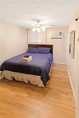 Laminate flooring and a functional window-mounted cooling unit define this practical sleeping space.