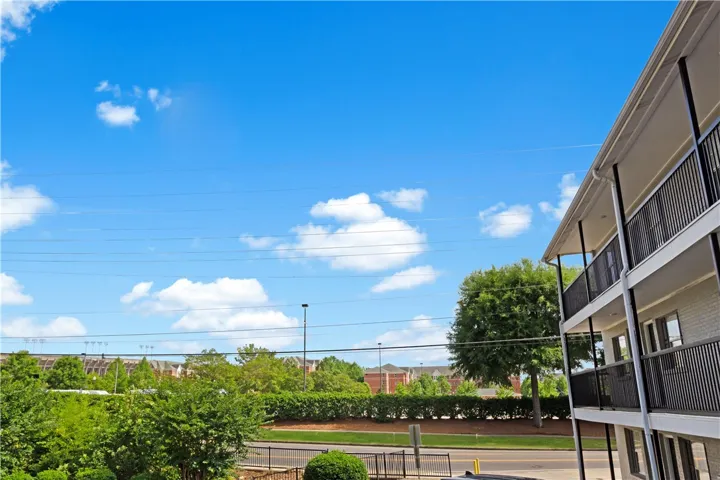 Upper floor balconies overlook a verdant street with distant community structures.