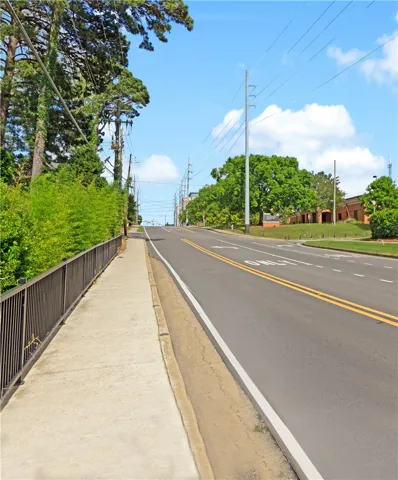 A well-maintained sidewalk with a protective fence runs alongside a clear road under a vast blue sky.