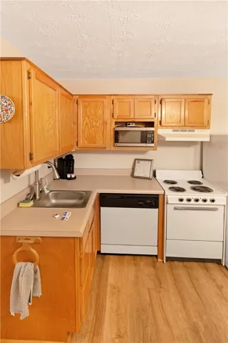 A compact kitchen with light wood cabinetry and functional appliances stands ready for culinary endeavors.