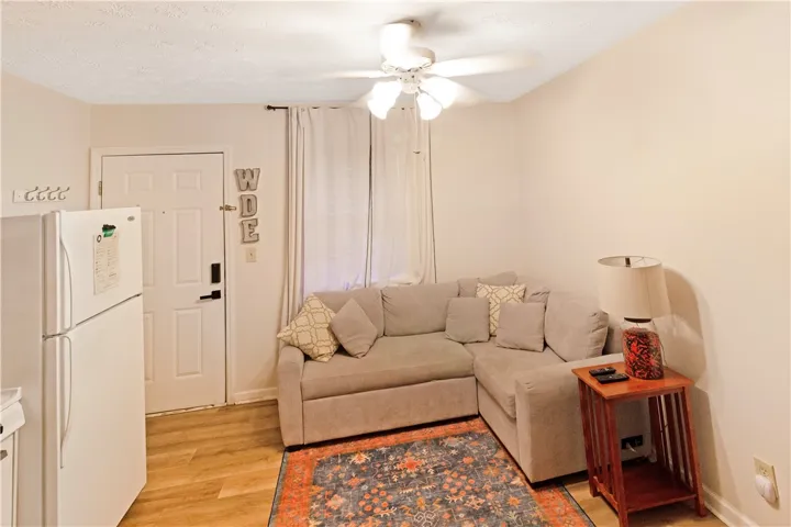 A compact living area with light wood flooring provides comfortable seating and an overhead ceiling fan.
