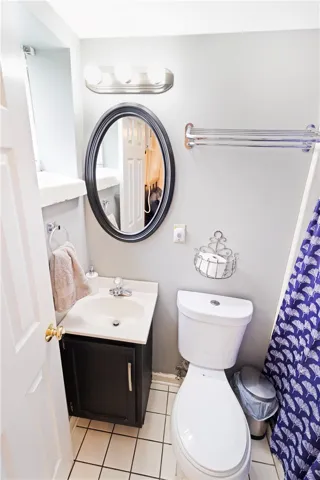 A compact bathroom offers functionality with a vanity, toilet, and tiled flooring.