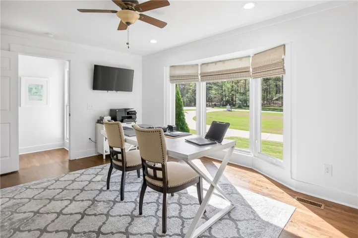 A quiet work area with hardwood floors, recessed lighting, and a picturesque view of the verdant lawn.