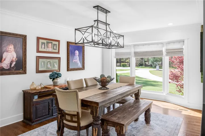 A rustic dining table anchors this well-lit room, offering pleasant views of the lush, green landscape.