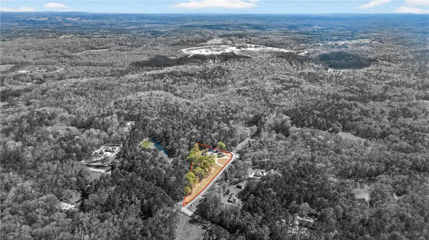An aerial panorama reveals a vast, wooded landscape surrounding a private lake, highlighting the serene natural environment.