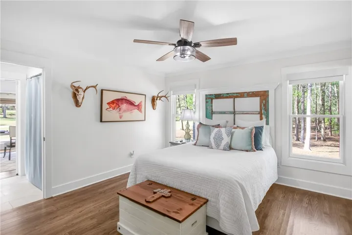 A tranquil bedroom retreat features rich wood flooring and a refreshing ceiling fan.