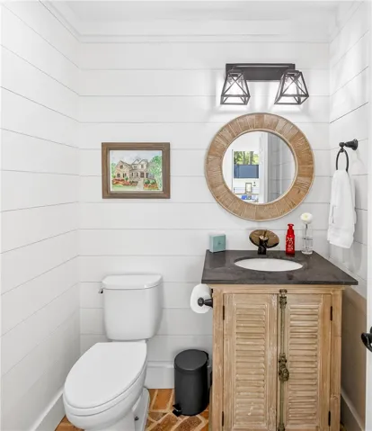 Clean lines define this powder room, featuring shiplap walls and a rustic vanity with a circular mirror.