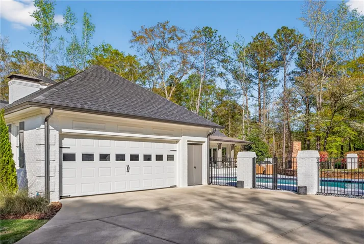 A classic white brick exterior with a substantial garage and a secluded pool area.