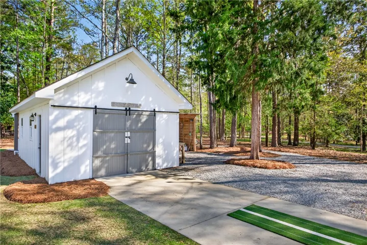 White siding and barn doors elevate this modern storage building amidst natural landscaping.