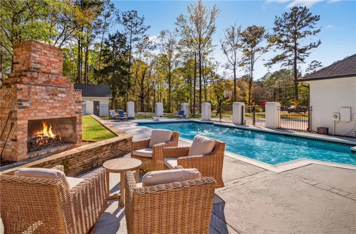 An inviting outdoor fireplace complements the refreshing pool and patio area, perfect for entertaining.