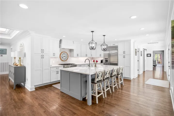 A central island anchors this spacious kitchen, featuring gleaming hardwood floors and sleek, modern appliances.