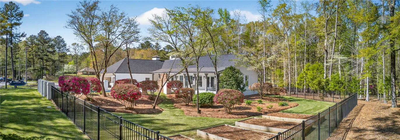A private, landscaped property with a fence separating manicured lawn from a wooded area.
