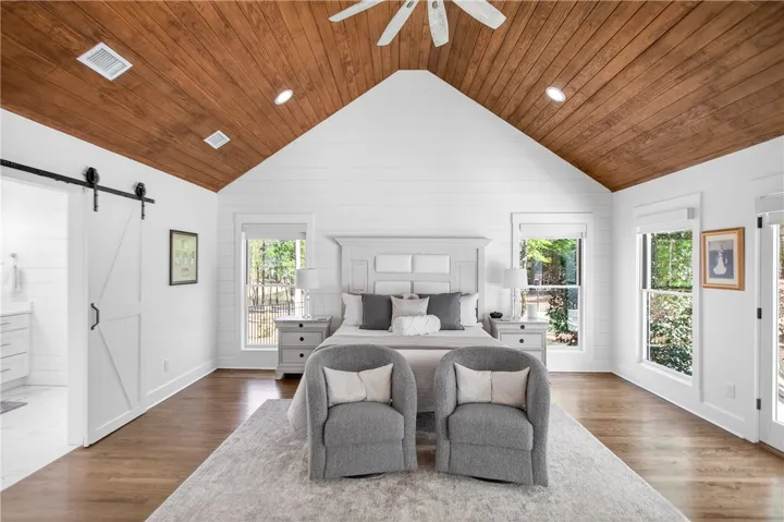 A spacious primary bedroom features rich wood vaulted ceilings and abundant natural light.