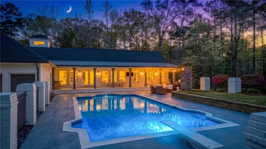 An inviting backyard oasis features a shimmering pool and covered patio for evening relaxation.